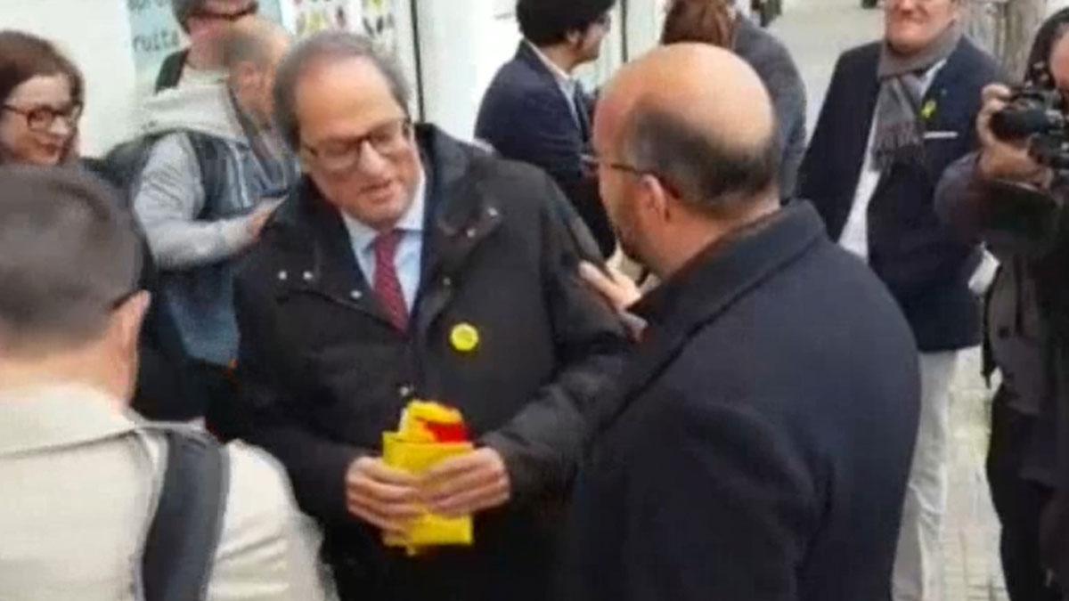 Un concejal del PP da una bandera de España a Torra en un acto en El Prat