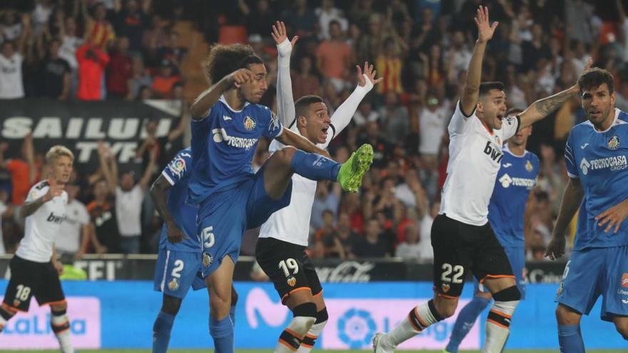 Los jugadores del Valencia protestan mientras el infractor Cucurella despeja.