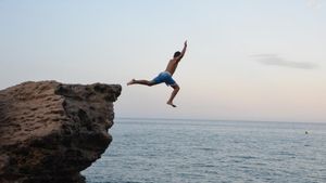 Un chico salta desde una roca de la Costa Brava.