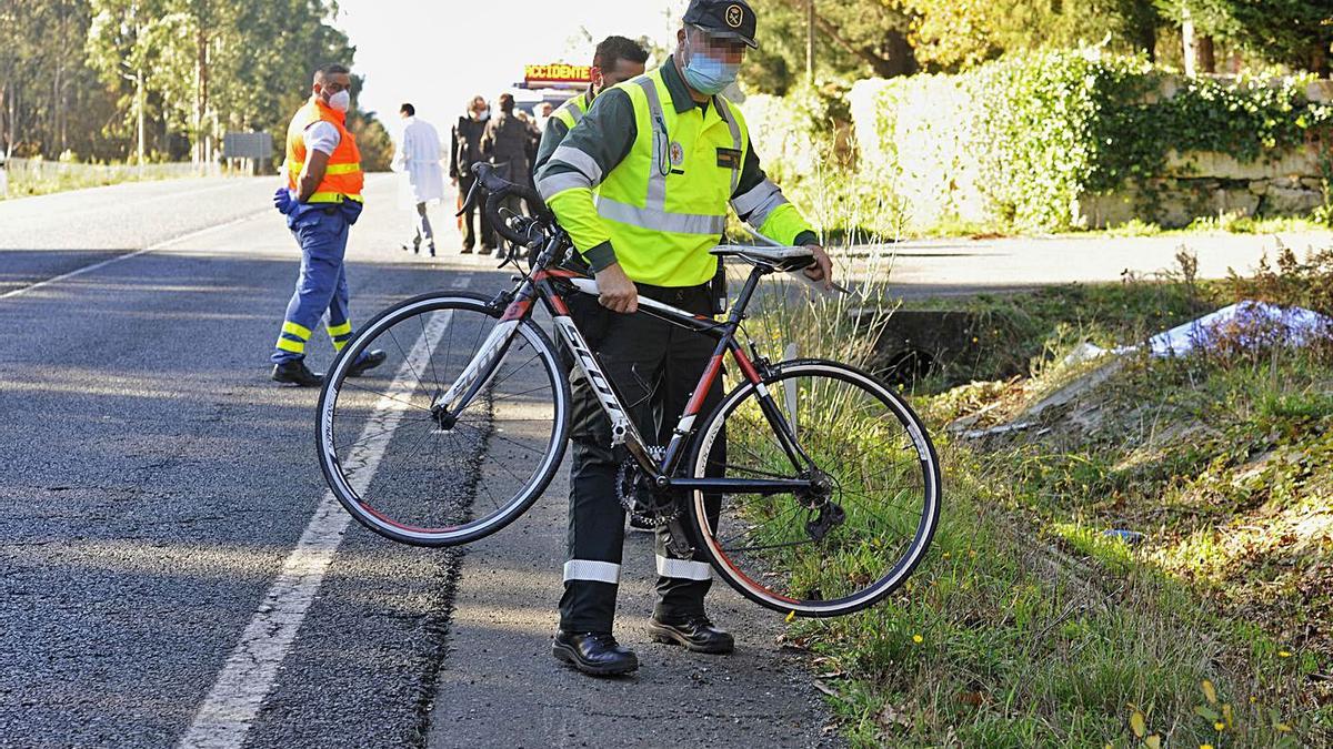 Un guardia retira la bicicleta de la cuneta en donde perdió la vida Alberto Vilariño. // FOTOS: BERNABÉ/JAVIER LALÍN