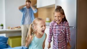 Niños gritando con su padre al fondo