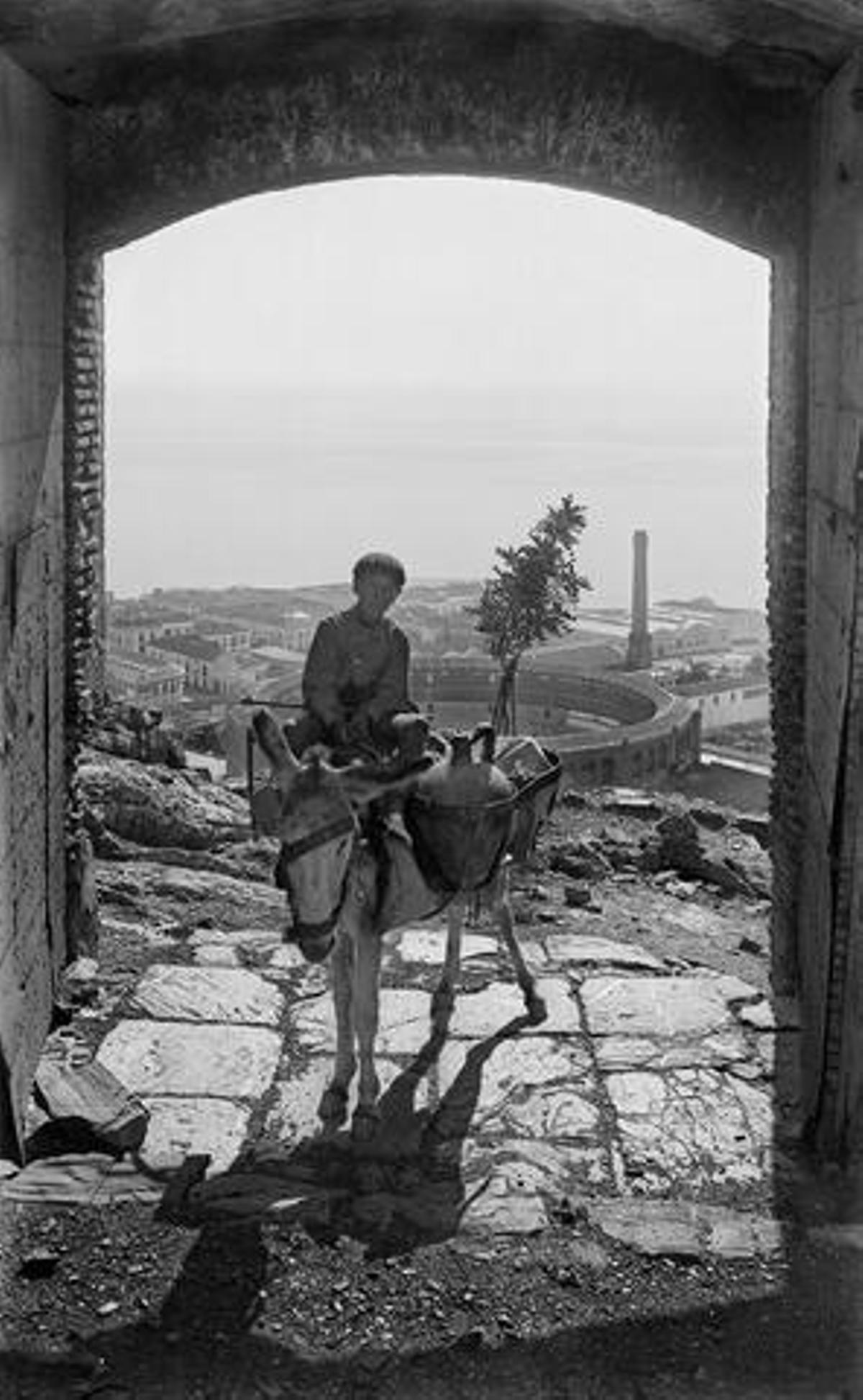 Vista de La Malagueta desde una puerta de acceso al castillo de Gibralfaro, desde el interior del castillo. En el centro de la imagen, un arriero que transporta cántaros