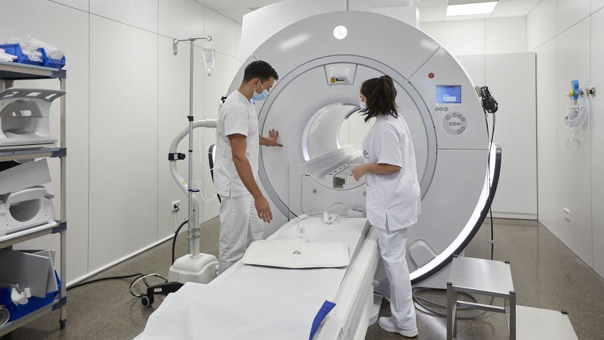Dos professionals sanitàris preparen un aparell de ressonància magnètica per fer una prova a Clínica Girona.