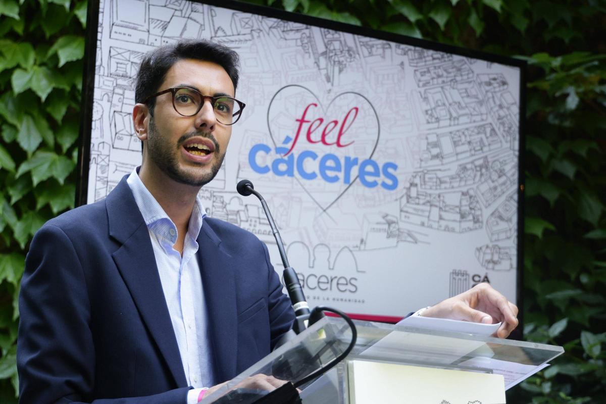 El concejal de Turismo, Ángel Orgaz, junto a una pantaña que muestra el nuevo logo 'Feel Cáceres'
