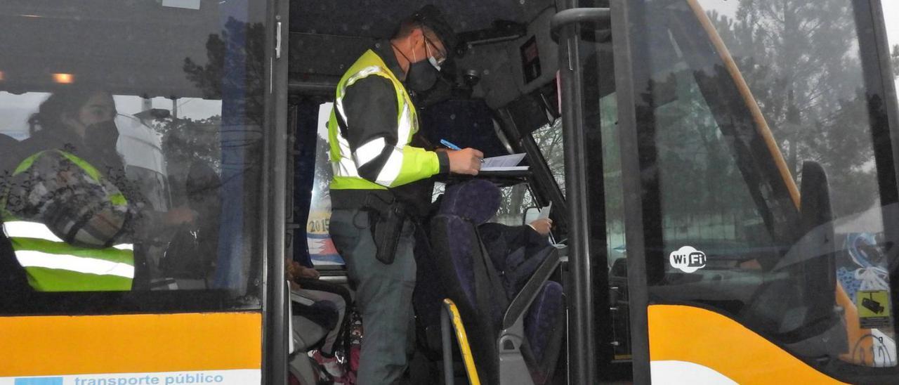 Un agente realiza la inspección de un autobús escolar, en Seixalbo. |   // FERNANDO CASANOVA