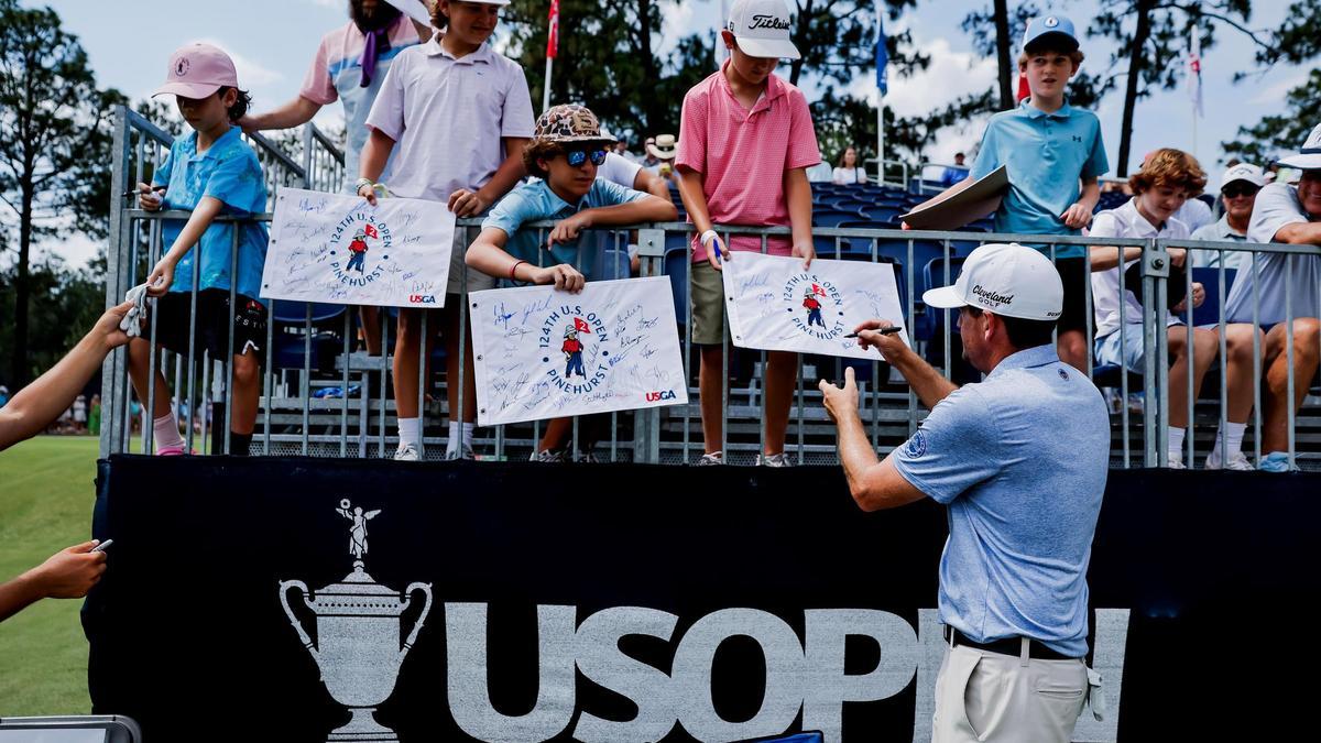 Keegan Bradley firma banderolas a unos niños en el inicio del US Open