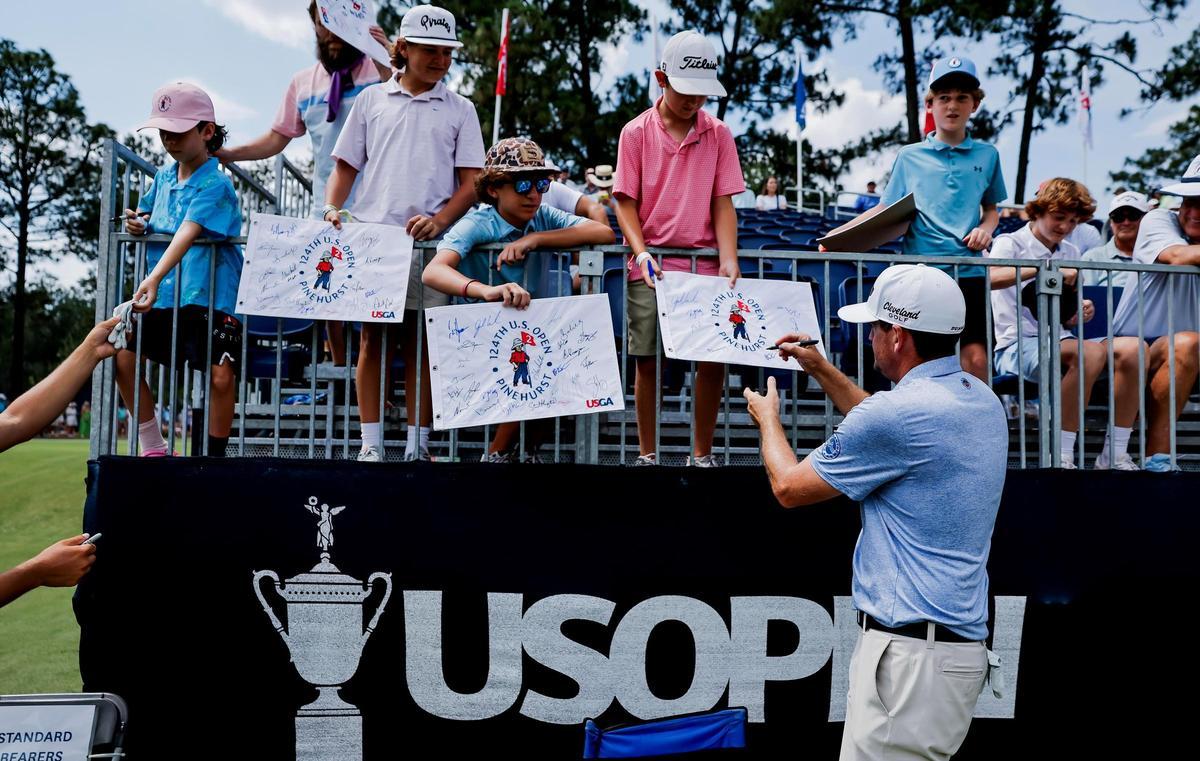 Keegan Bradley firma banderolas a unos niños en el inicio del US Open
