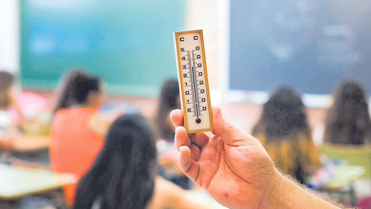 Un profesor con un termómetro en un instituto, en imagen de archivo.
