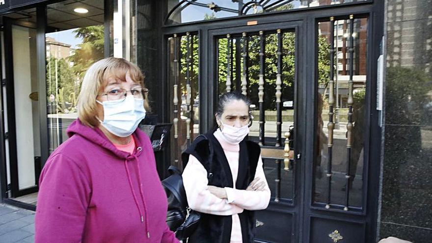 Dos vecinas pasan junto al portal de las dos mujeres en El Llano. | Á. González