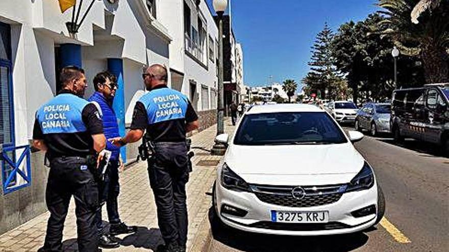 David Duarte (centro), ayer, junto a dos policías locales de Arrecife. Al lado, uno de los vehículos patrulla de alquiler.