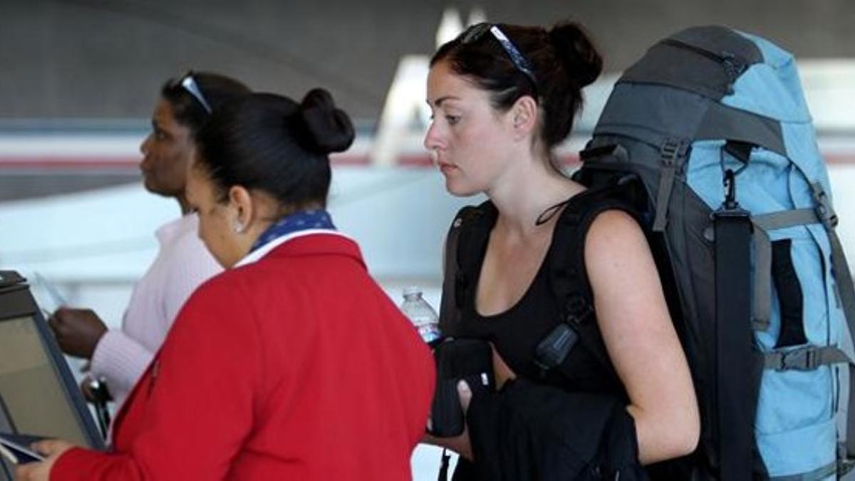 Una empleada de American Airlines atiende a una pasajera antes de embarcar en un vuelo en Los Ángeles, este lunes.