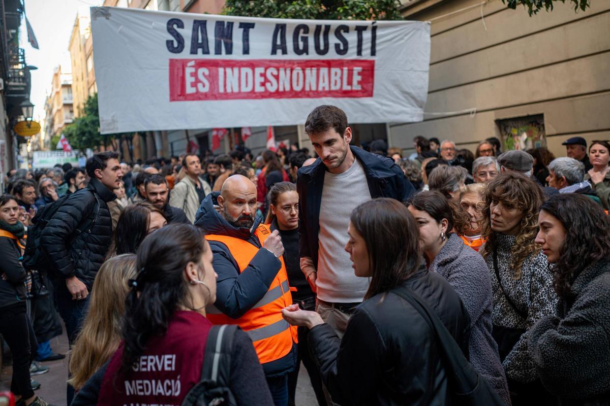 Varias personas hablan con Txema, en el centro, minutos antes del supuesto desalojo —que finalmente no se llevó a cabo— del bloque Sant Agustí, en el barrio de Gràcia, el 25 de marzo de 20266