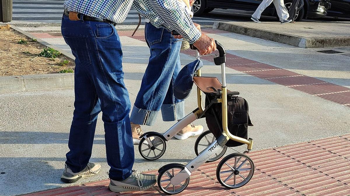 Un hombre camina con la ayuda de un andador en Bueu.