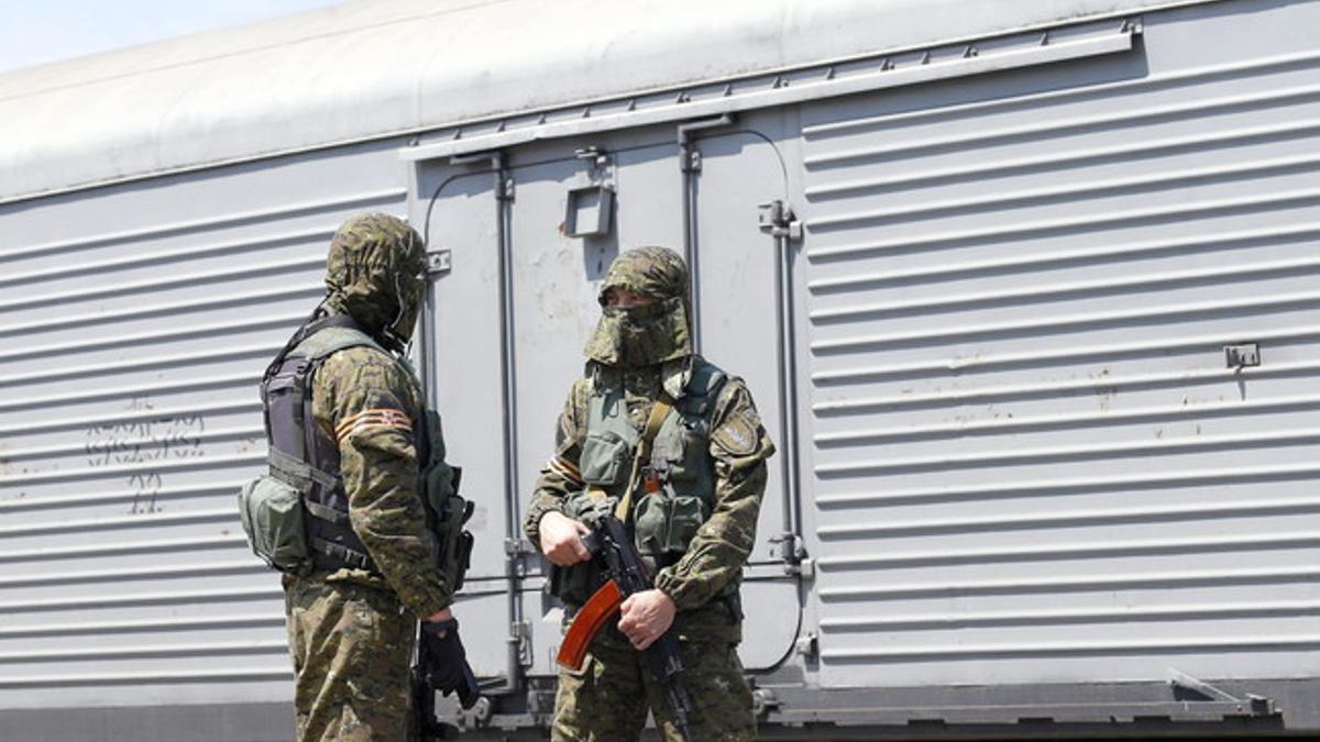 Soldados rebeldes montan guardia ante un vagón refrigerado que transporta a víctimas del avión de Malaysia Airlines, este domingo en Torez (Donetsk).