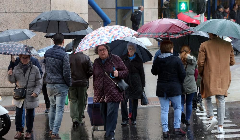 Viandantes tratan de protegerse de la lluvia, en el centro de Vigo