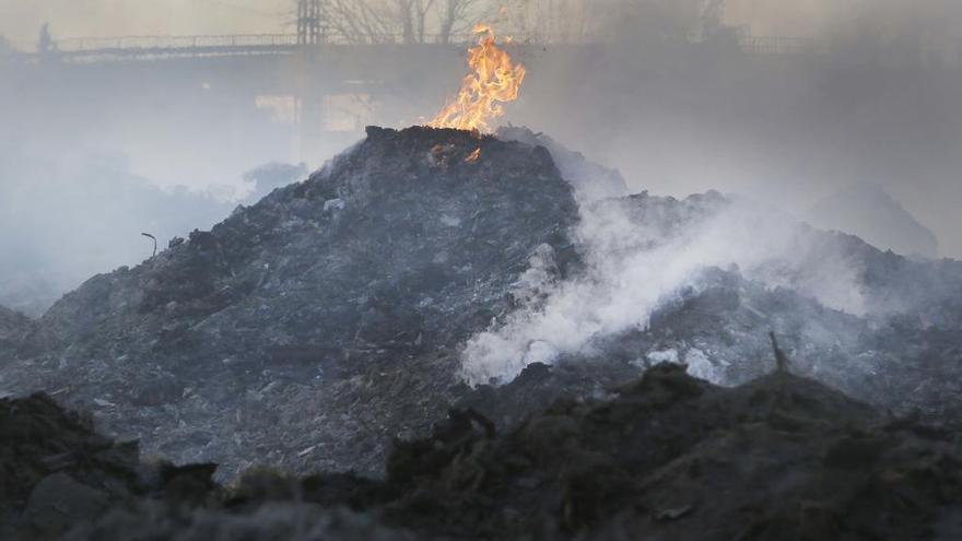 Las llamas todavía son visibles cuando sopla el viento entre montañas de residuos en combustión.