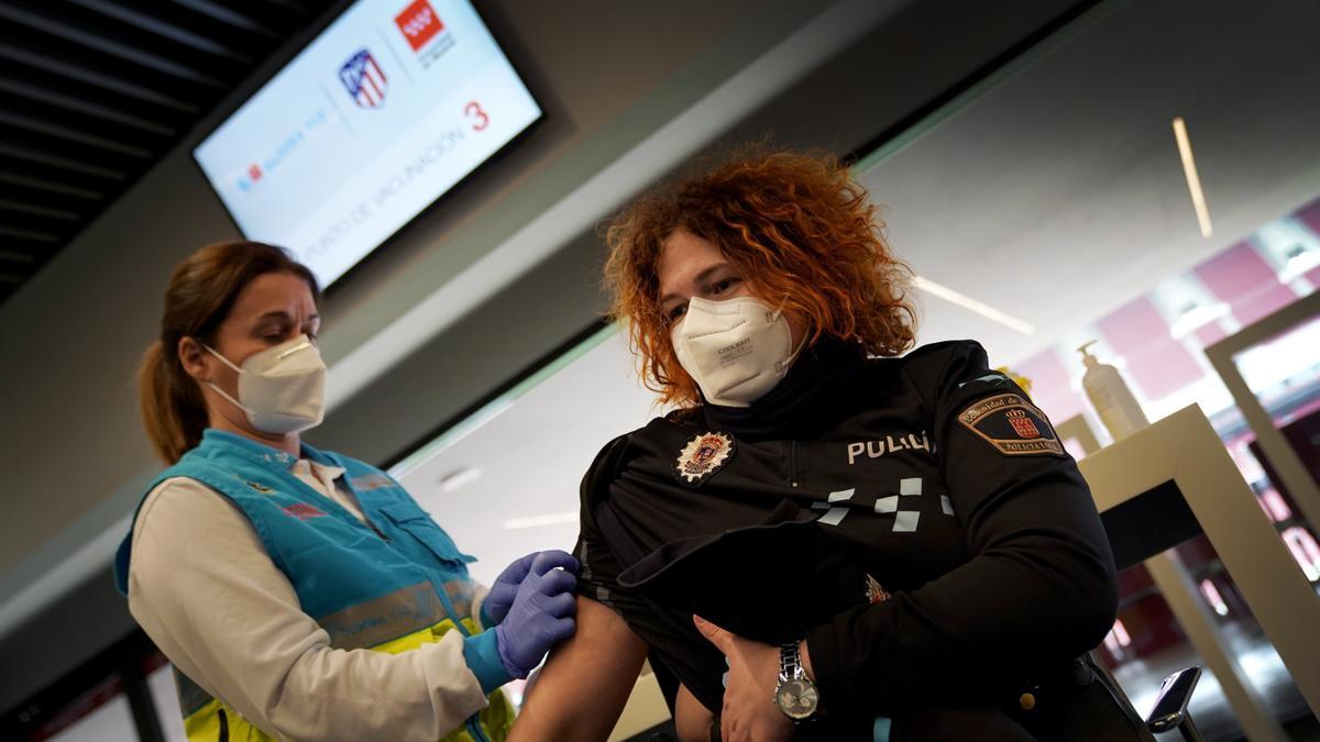 Una sanitaria administra una vacuna a una policía.