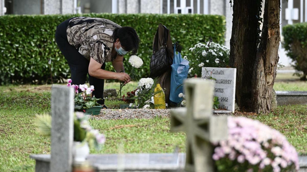 Una mujer atiende la tumba de un ser querido en el cementerio de San Mauro, Pontevedra. |   // RAFA VÁZQUEZ