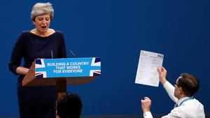 Un espontáneo entrega una hoja de despido a la primera ministra británica, Theresa May, durante su discurso de clausura de la conferencia del Partido Conservador en Manchester.