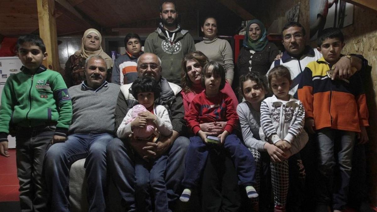 Dimitris Spiridis (en primera fila, tercero por la izquierda), junto a su mujer, Maria, y varios miembros de las dos familias sirias que acoge en su casa, en Evropos, cerca de Idomeni, este lunes.