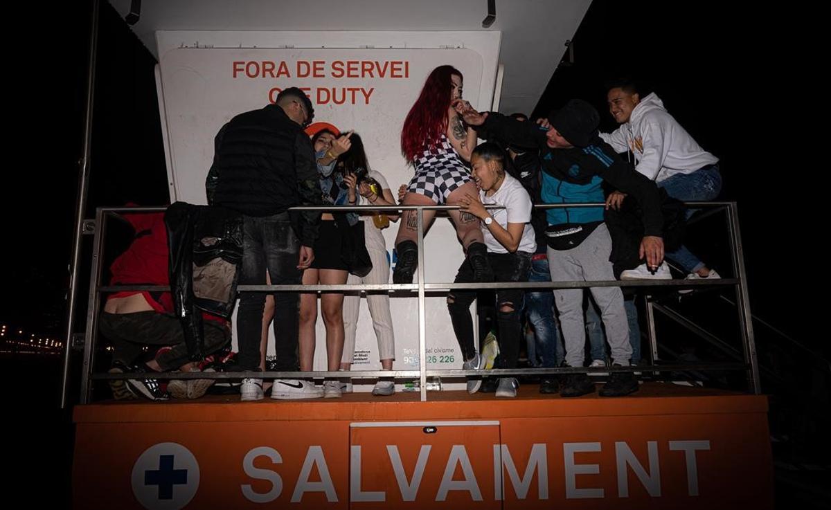 Jóvenes de fiesta en una de las casetas de salvamento de los socorristas, en la playa de la Barceloneta.