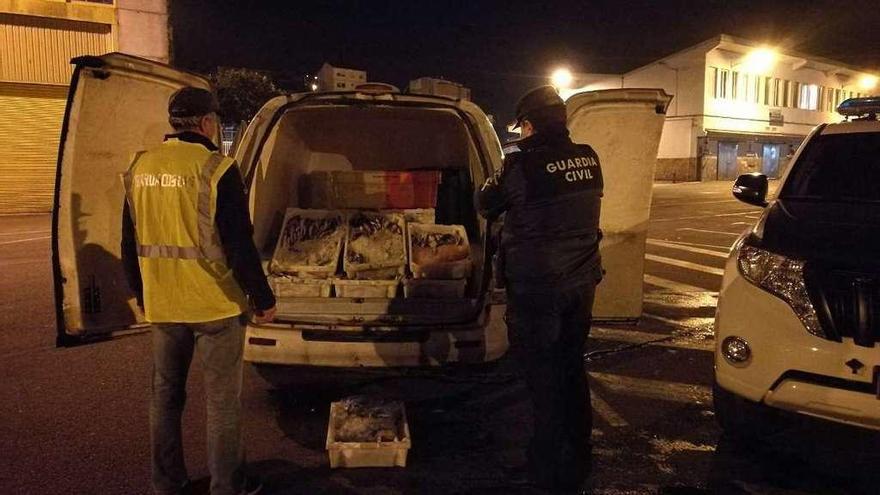 Agentes de la Guardia Civil y del Servicio de Guardacostas ante la mercancía incautada en Marín. // FdV
