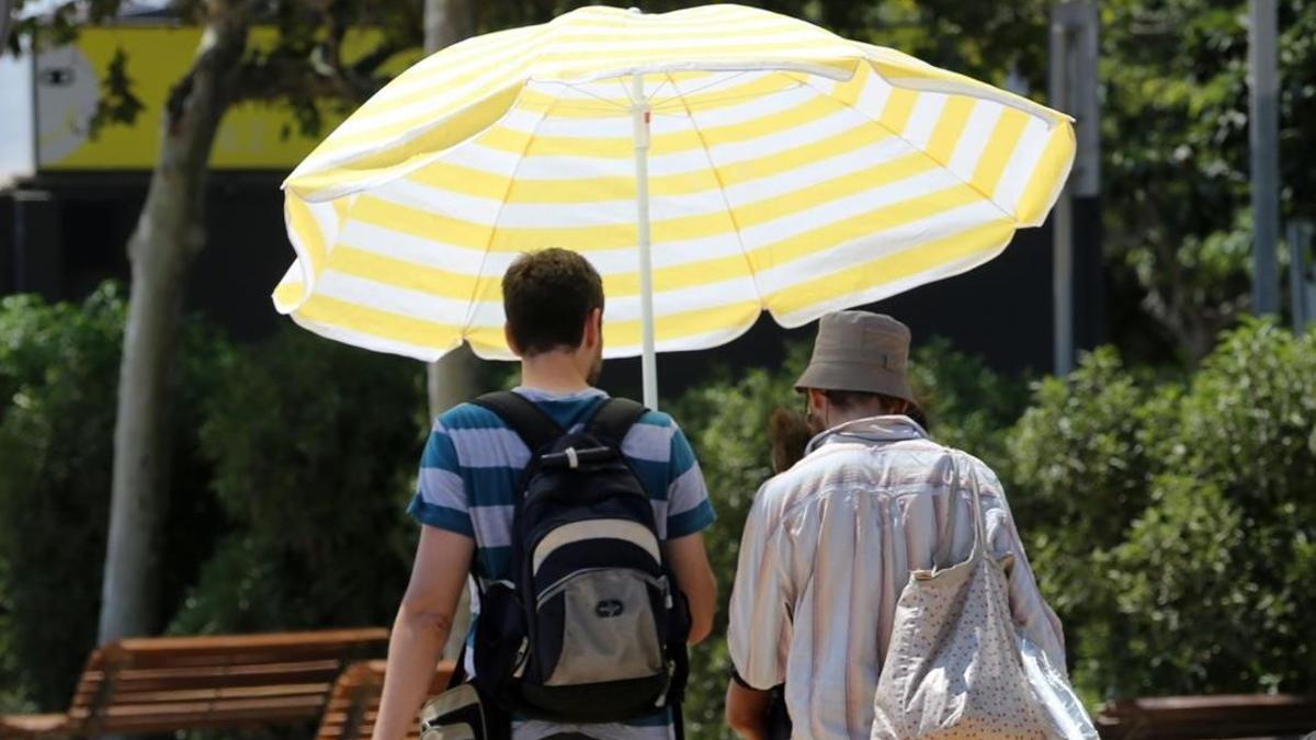 Turistas pasean con una sombrilla por Barcelona