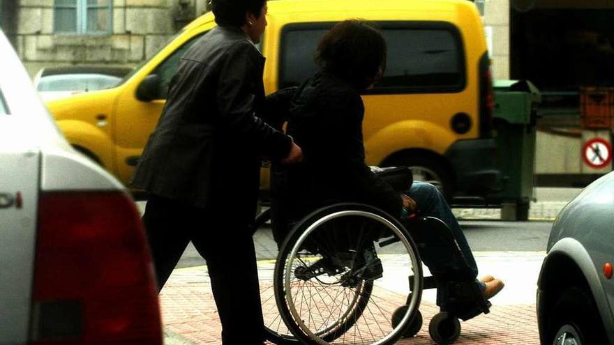 Una mujer traslada a una joven en silla de ruedas.