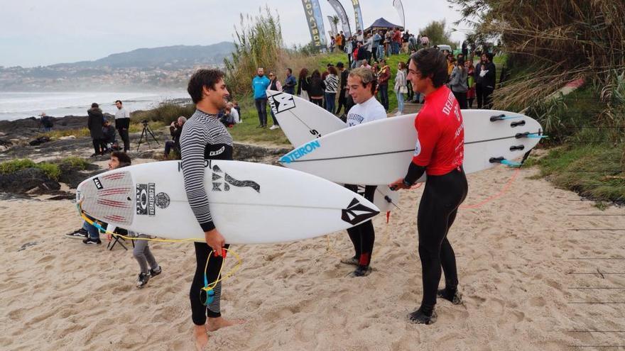 Gony Zubizarreta (izqda.) charla con otros surfistas en una visita anterior a la playa de Patos. // José Lores