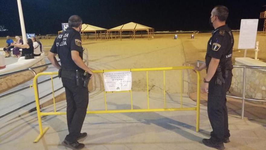 Agentes de la Policía Local tras colocar la valla que impedía el acceso nocturno a los arenales. | LEVANTE-EMV