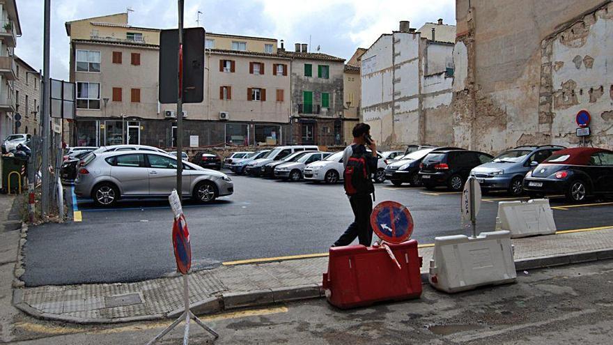 Un peatón circula ante el aparcamiento de Bisbe Pere Cima que luce nuevo tras ser asfaltado y pintadas las plazas de aparcamiento.