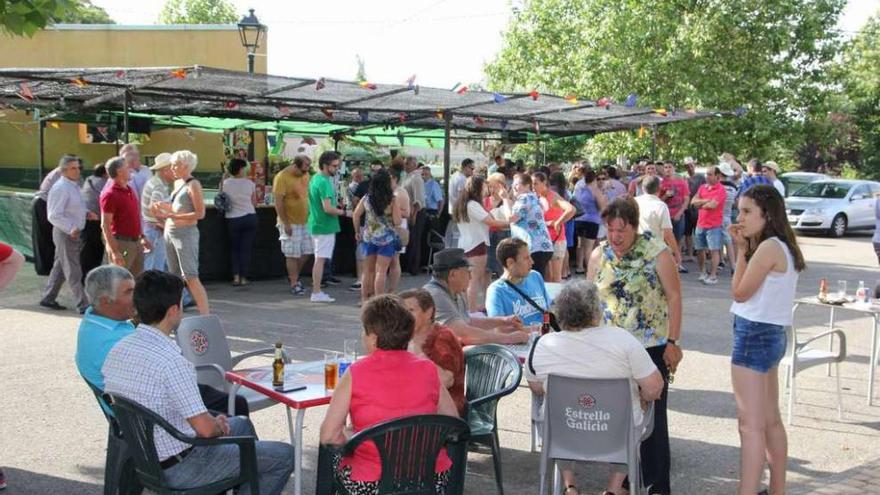 Grupos de personas buscan la sombra y bebida durante la degustación de la ternera de Aliste.