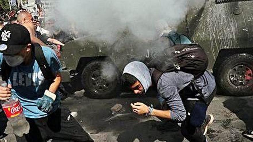 Un grup de manifestants fuig del gas lacrimogen durant una protesta a Santiago de Xile