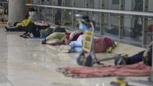 People sleep on the floor of Terminal 4 at Adolfo Suarez-Madrid Barajas Airport in Madrid, Spain, Thursday, May 15, 2025. (AP Photo/Manu Fernandez). EDITORIAL USE ONLY/ONLY ITALY AND SPAIN