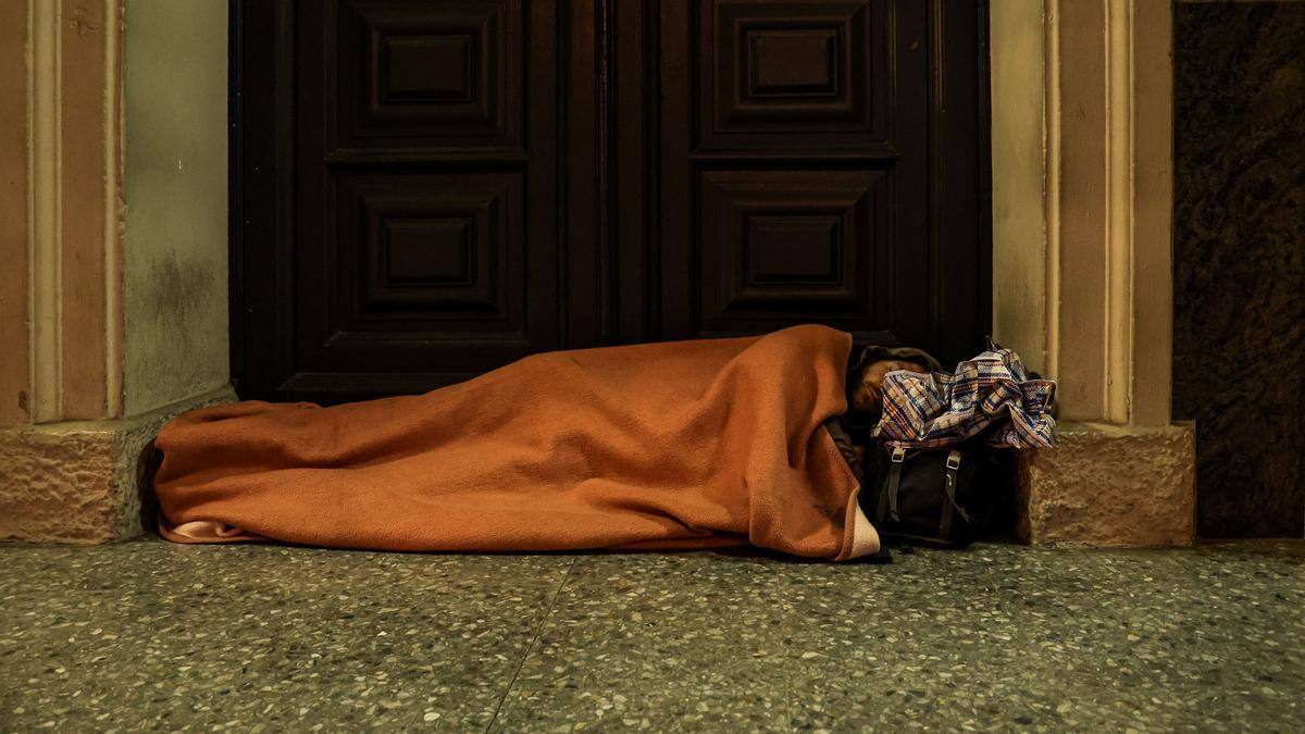 Un hombre duerme en las escaleras de una iglesia de l'Hospitalet de Llobregat.