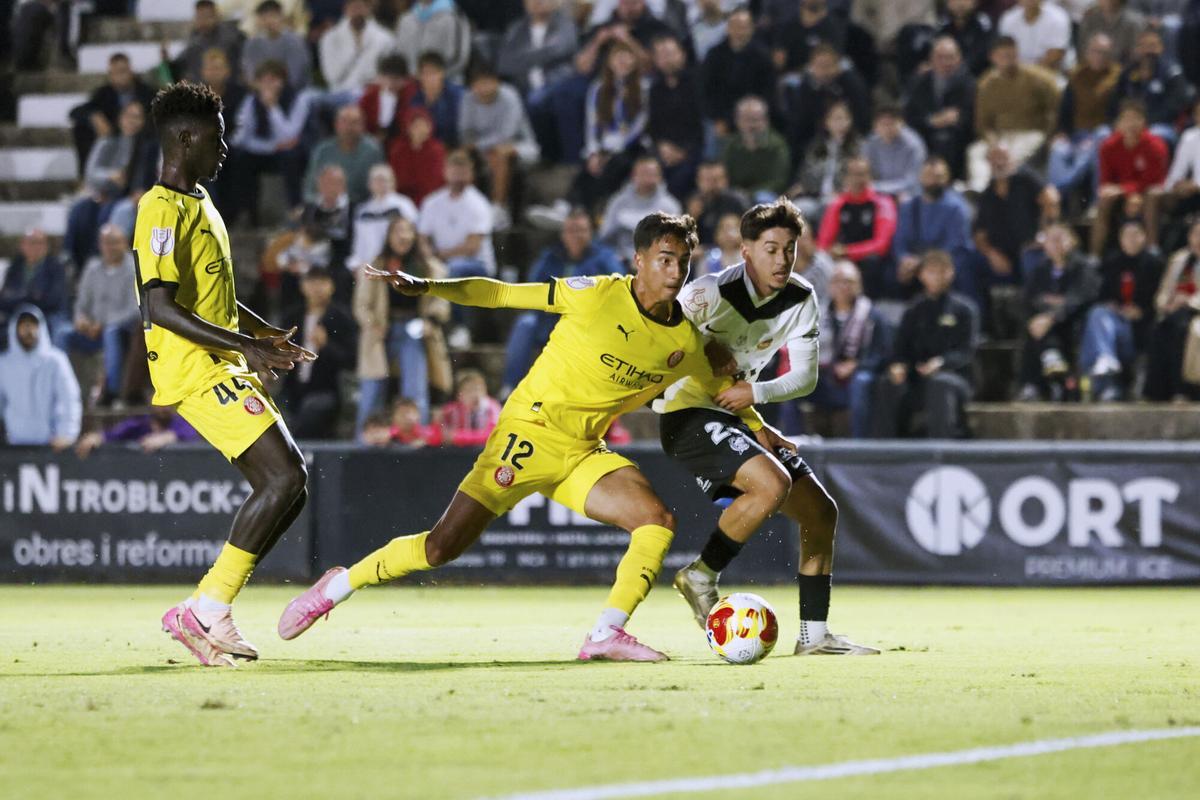INCA (ISLAS BALEARES), 28/10/2025.- Pau García (d) del Constància pelea un balón ante Vitor Reis (c) del Girona durante el partido de primera ronda de la Copa del Rey que el CE Constància y el Girona FC disputan este martes, en el Nou Camp de Inca (Islas Baleares). EFE/ Cati Cladera