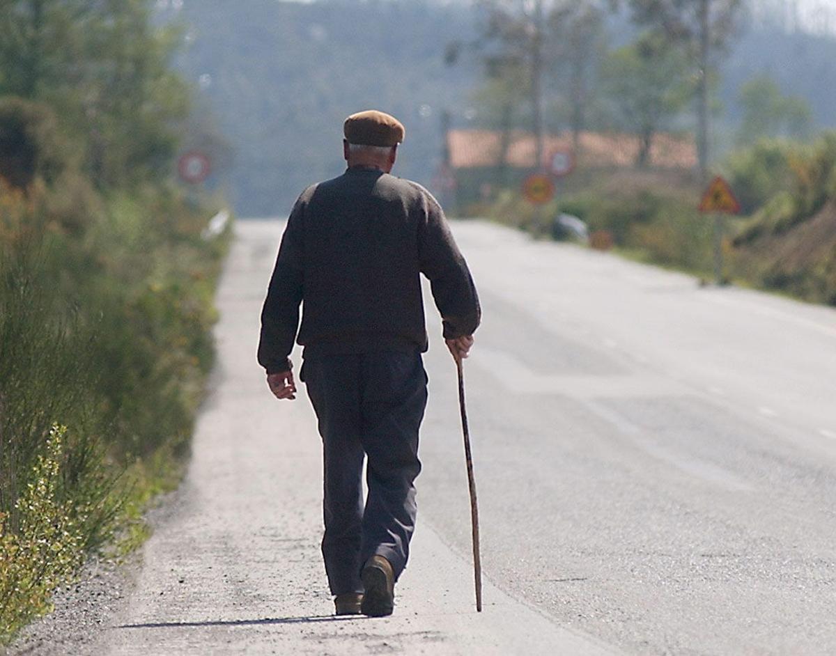 Un anciano camina por una zona rural.