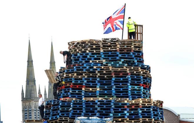 Los constructores de hogueras completan su estructura cerca del muro de la paz en el oeste de Belfast, Irlanda del Norte, antes de las tradicionales hogueras de la 11ª noche. - La Undécima Noche se refiere a la noche antes del 12 de julio.