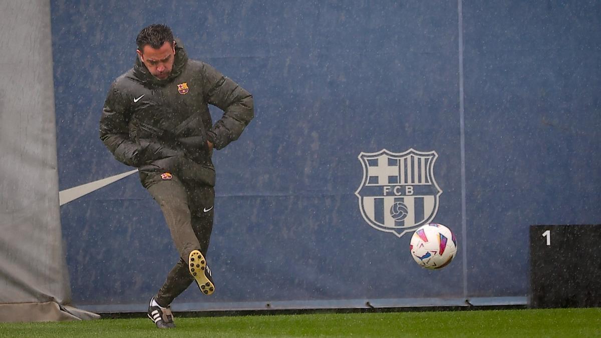 Xavi devuelve el balón a los futbolistas en el campo de entrenamiento.