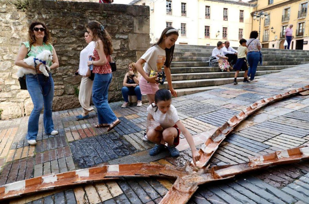 El scalextric de tejas de Benjamín Menéndez, a la izquierda. Y niños jjugando , a la derecha. gando en el pu | MARA VILLAMUZA