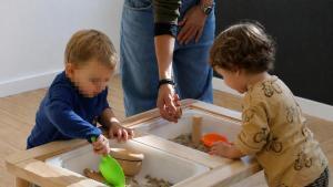 Dos nens duna llar dinfants rural experimentant amb diversos materials, en una imatge darxiu.