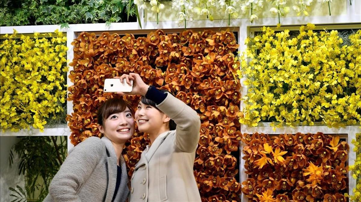 Dos chicas se hacen un selfi en una feria de flores en Japón.