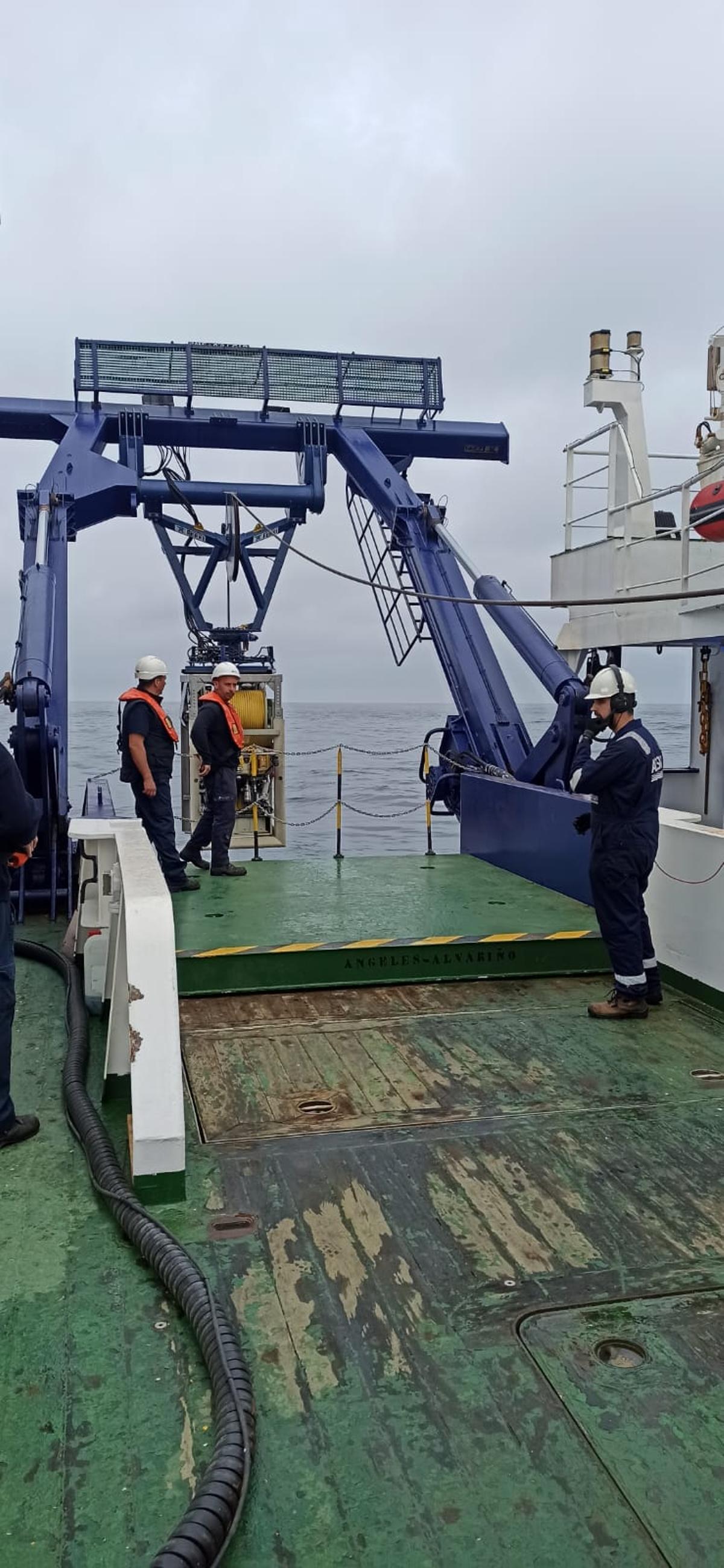 Tres tripulantes del “Ángeles Alvariño”, bajando el robot submarino.