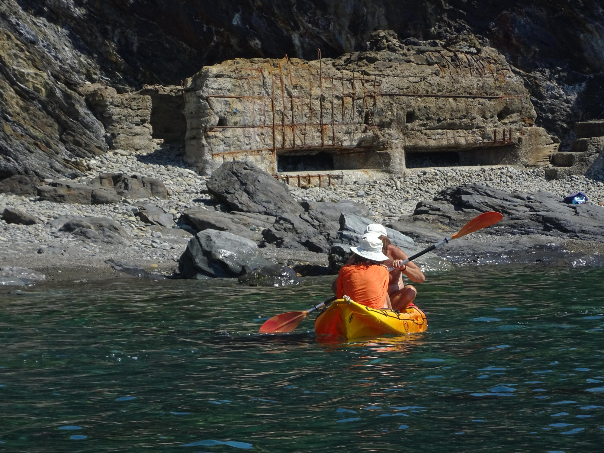 Unes caiaquistes remant, a Portbou, davant del búnquer de les Tres Platgetes castigat per la salabror del mar.jpg