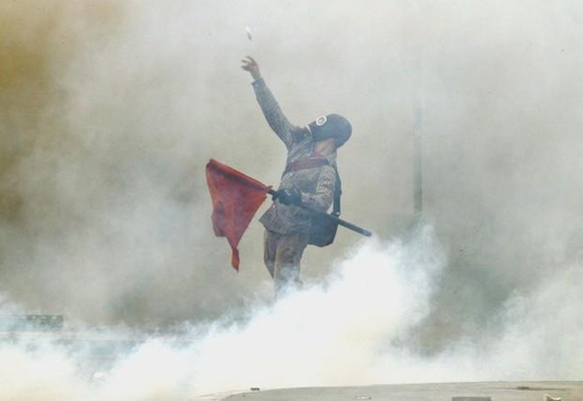 Demonstrator hurls projectiles at riot police during nationwide strike over austerity measures in Athens