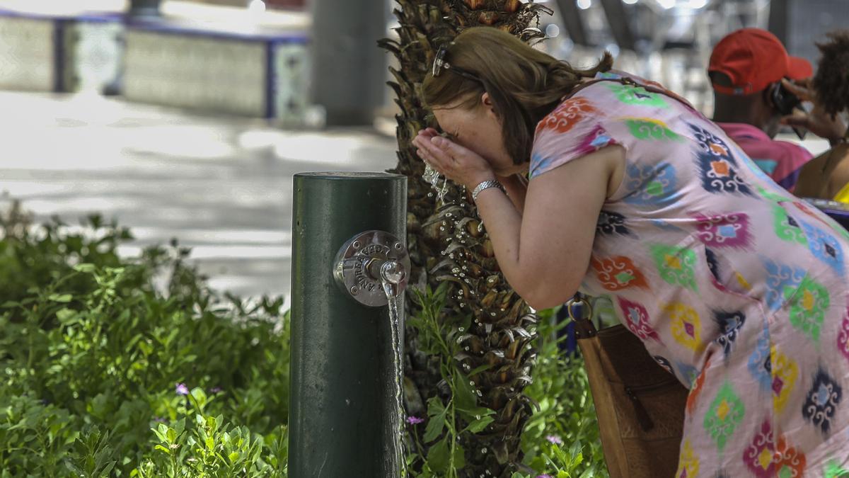 Una mujer se refresca en una fuente de la Glorieta en Elche