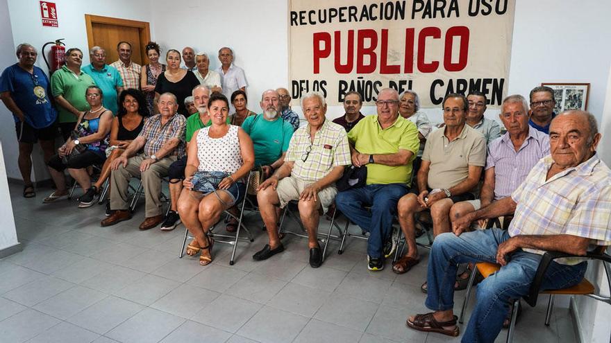 Vecinos y dirigentes vecinales, esta semana en la sede de Pedregalejo con un antiguo cartel que reivindica el uso público del balneario.