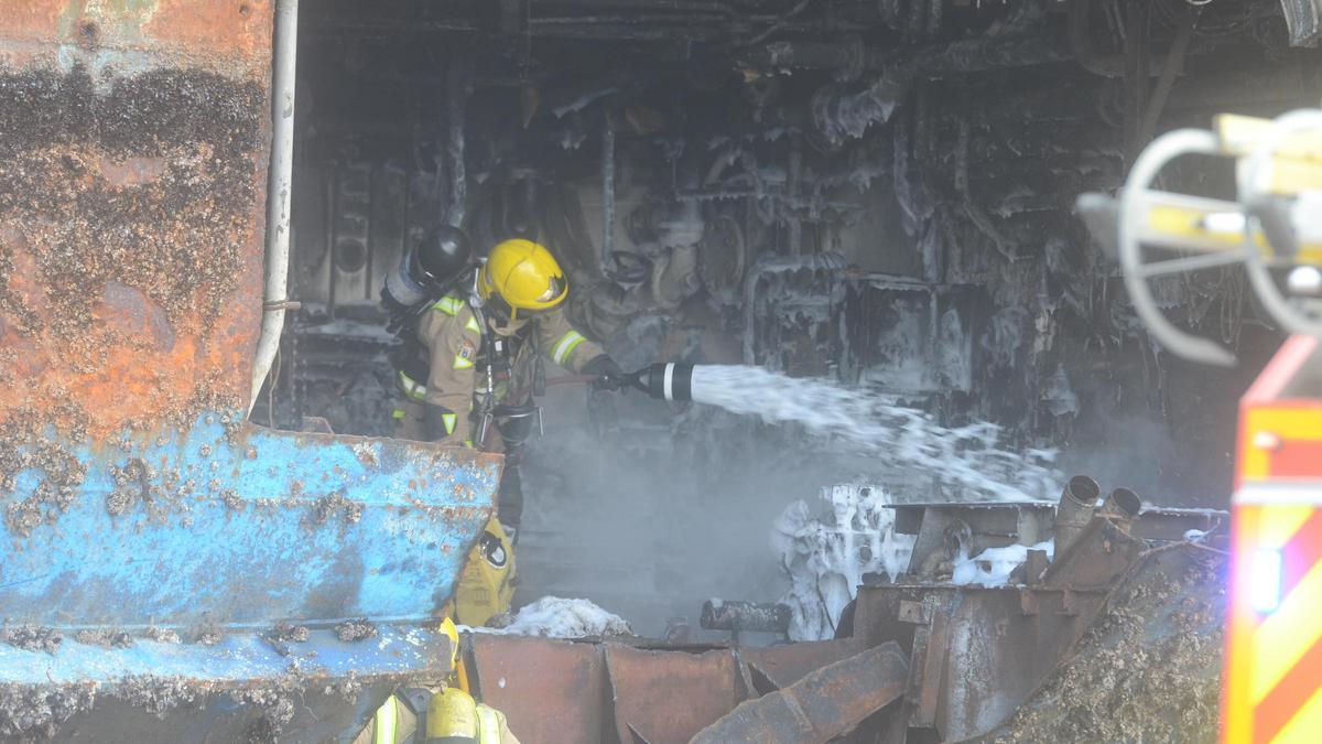 Un bombero intenta sofocar los restos de llama y enfriar la zona