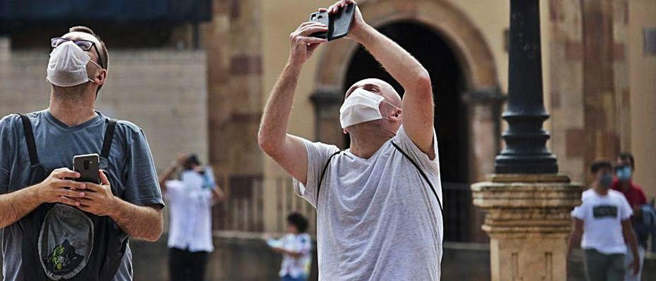 Dos turistas, haciendo fotos en la plaza de la Catedral.