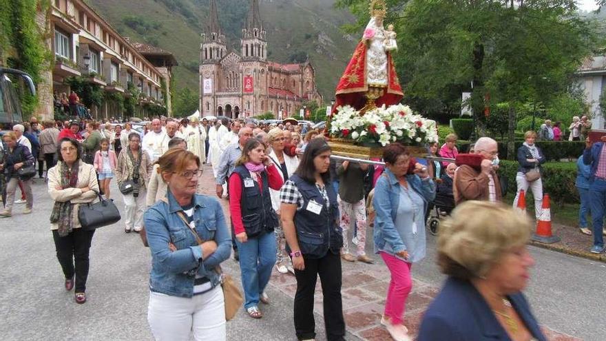 Una marea de fieles, arropando ayer a la Virgen de Covadonga. Abajo, el párroco Manuel García oficia la novena de la Virgen de la Cueva.